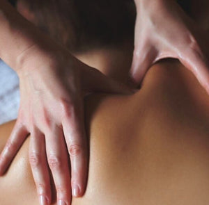 mão do massoterapeuta fazendo massagem nas costas do paciente