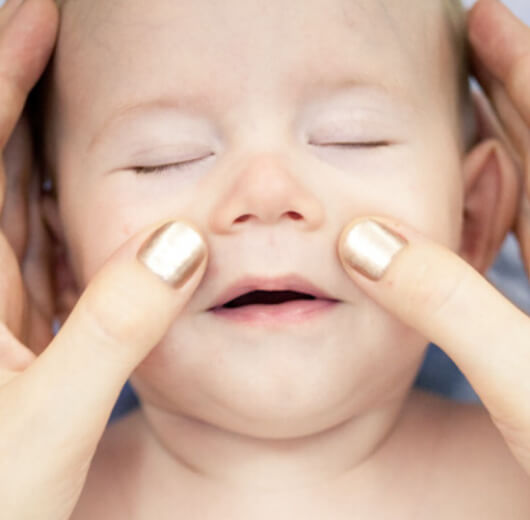 bebê recebendo massagem facial