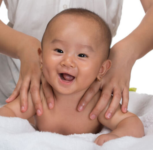 bebê sorrindo ao receber massagem nas costas