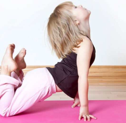criança fazendo pose de yoga no chão