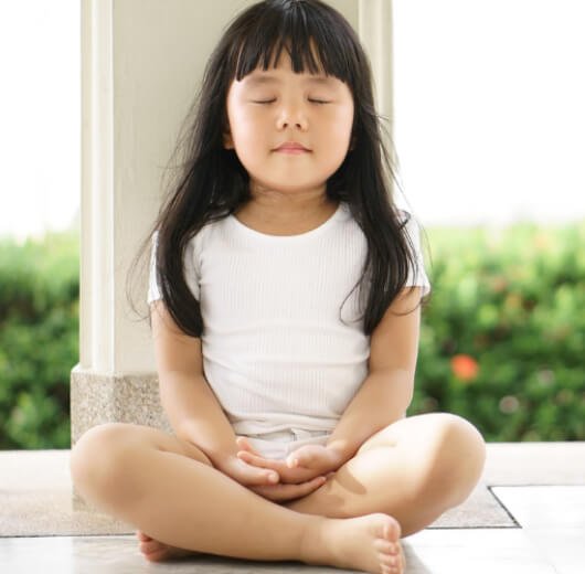 criança meditando sentada no chão